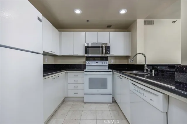 a kitchen with granite countertop white cabinets and stainless steel appliances