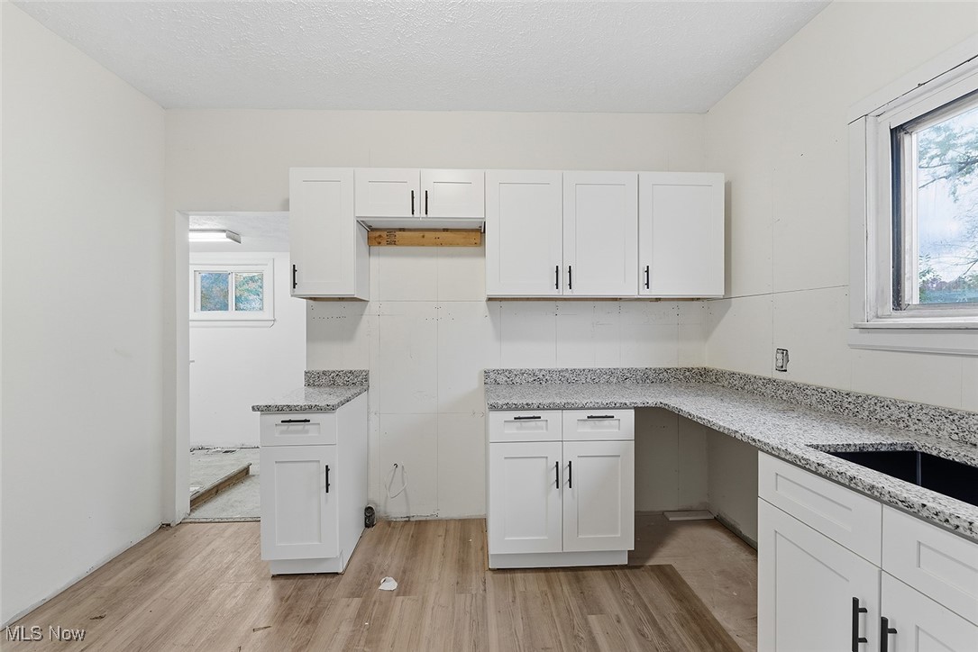 1206 Diagonal Road Akron, OH 44320 - Photo 13 of 28 Kitchen with white cabinets, light wood-type flooring, light stone countertops, and a textured ceiling