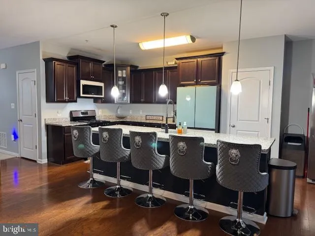 a kitchen with stainless steel appliances kitchen island granite countertop a refrigerator a sink a stove and oven with wooden floor