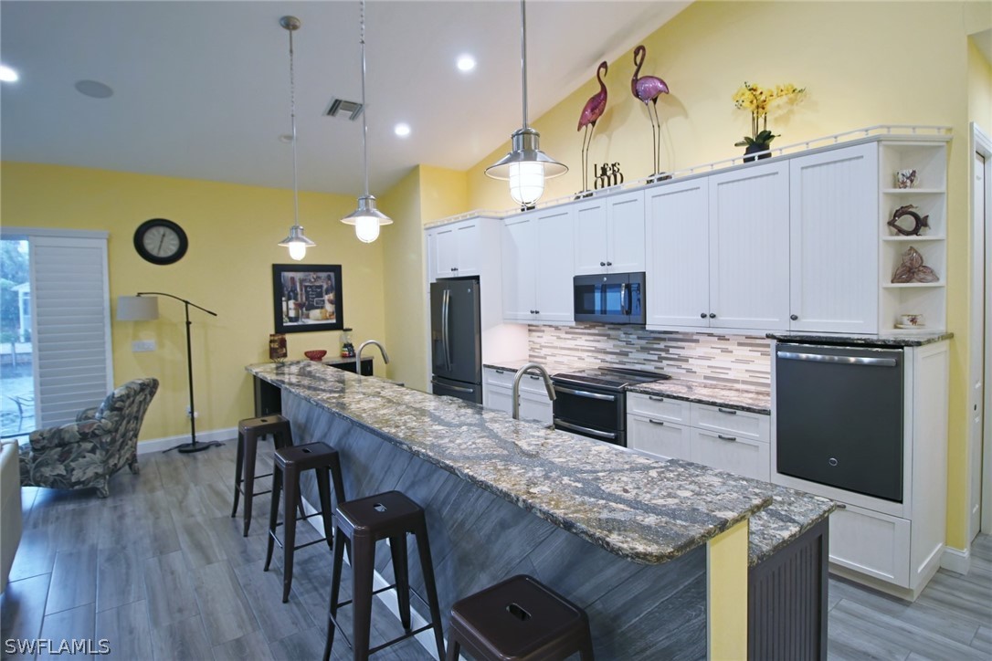 2743 Janet Street Cape Coral, FL 33993 - Photo 12 of 35 a kitchen with stainless steel appliances granite countertop a stove a sink dishwasher and a refrigerator with wooden floor