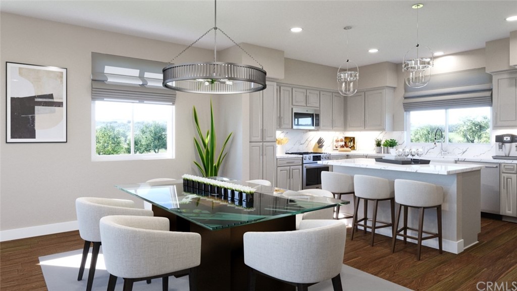 a kitchen with stainless steel appliances granite countertop a dining table chairs wooden floor and a window