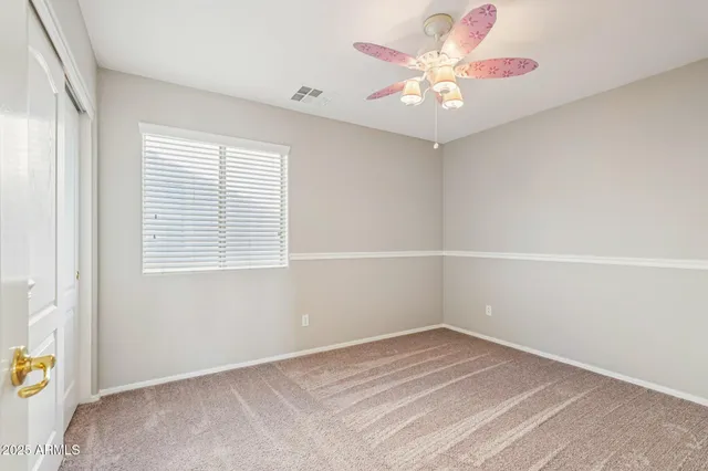 an empty room with a window and a fan