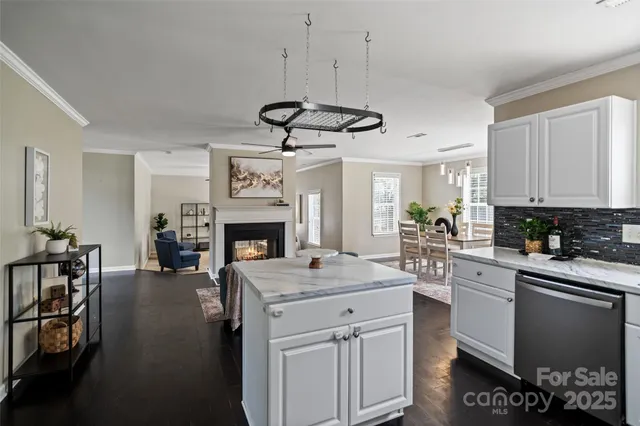 a kitchen with a chandelier a stove a sink dishwasher and white cabinets with wooden floor