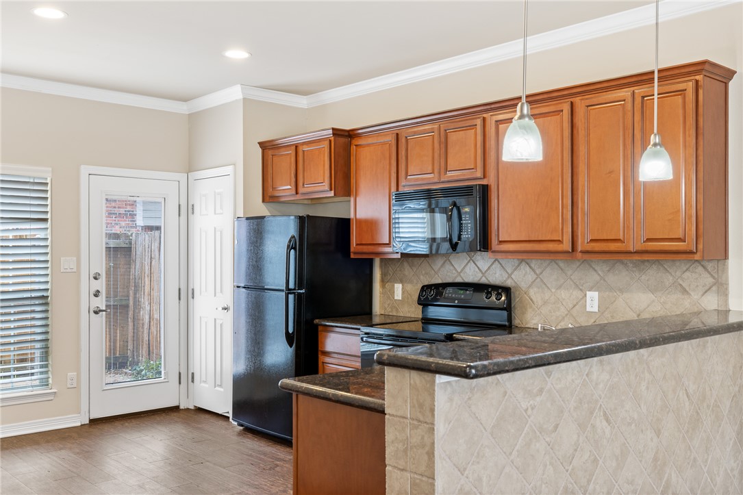 1198 Jones-Butler Road, Unit 1003 College Station, TX 77840 - Photo 4 of 42 a kitchen with stainless steel appliances granite countertop a refrigerator a stove and a sink with wooden floor
