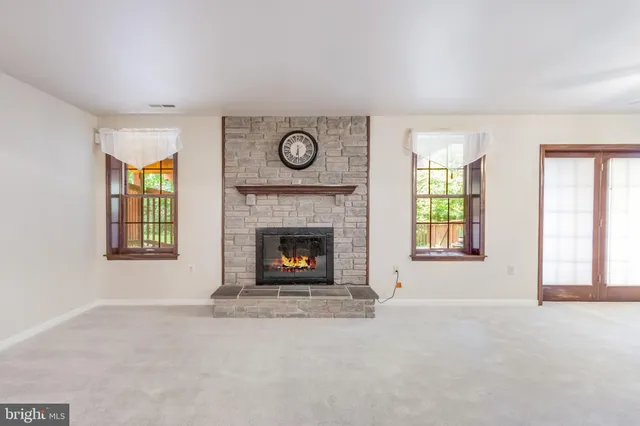 an empty room with windows and fireplace
