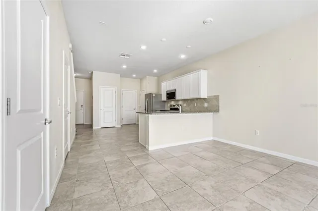 a view of a kitchen with refrigerator and white cabinets