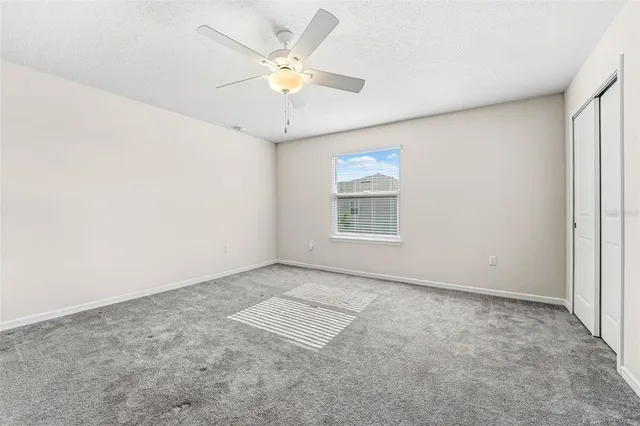 an empty room with windows and fan