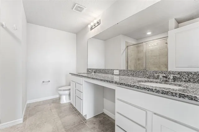 a bathroom with a granite countertop sink and a toilet