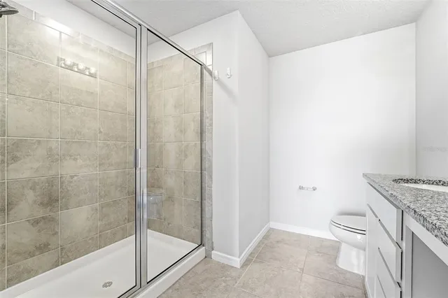 a bathroom with a granite countertop sink a toilet and shower