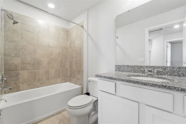 a bathroom with a granite countertop sink a toilet and bathtub