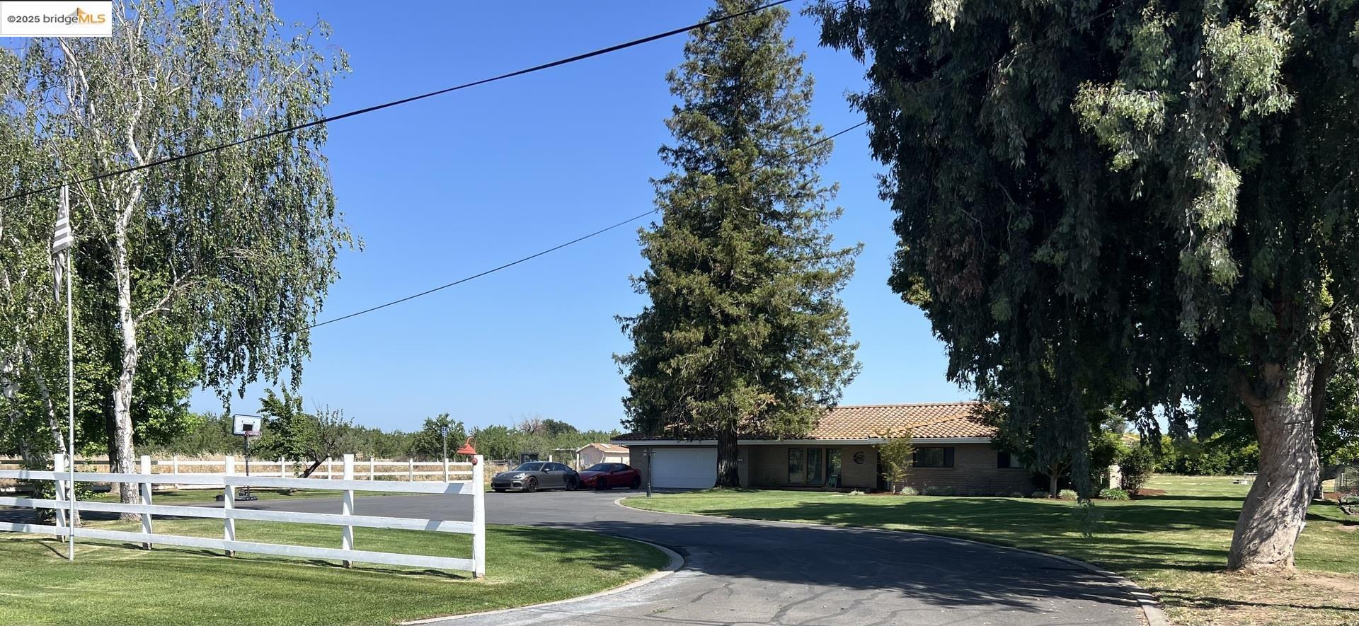 a view of a house with a big yard and large trees