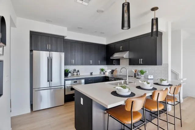 a kitchen with a refrigerator a stove a sink and chairs