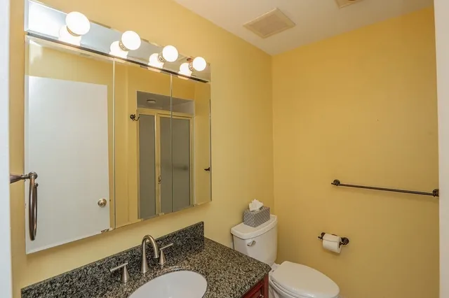 a bathroom with a granite countertop sink mirror vanity and toilet