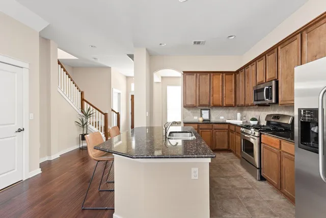 a kitchen with kitchen island granite countertop wooden floors granite counter tops and a view of living room