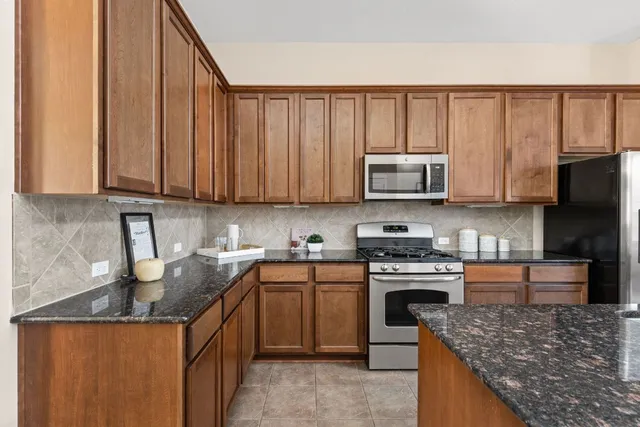 a kitchen with stainless steel appliances granite countertop a stove top oven microwave and refrigerator