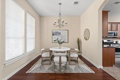 a dining room with wooden floor a chandelier a wooden table and chairs