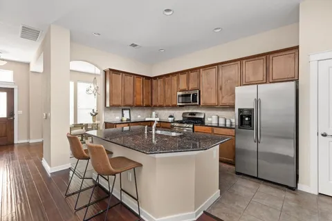 a kitchen with stainless steel appliances granite countertop a refrigerator a stove a sink a dining table and chairs