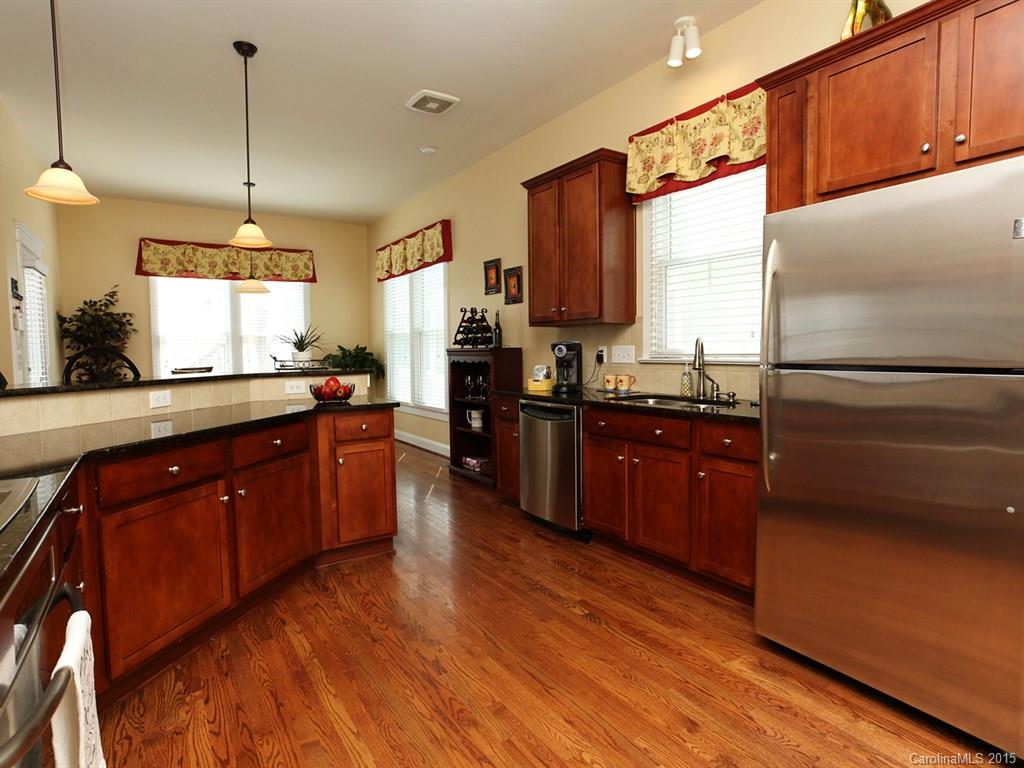 742 Revival Row Fort Mill, SC 29708 - Photo 12 of 24 a kitchen with stainless steel appliances granite countertop wooden cabinets a refrigerator a sink a stove and a wooden floors