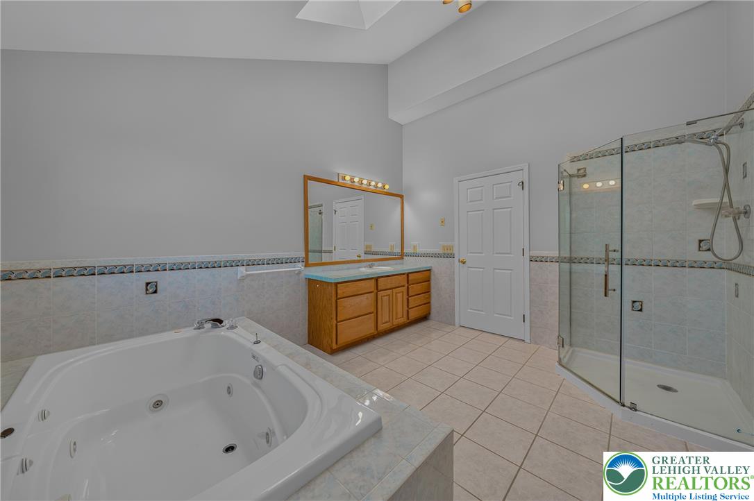 630 Clearfield Road Nazareth, PA 18064 - Photo 52 of 100 Tiled flooring and vaulted ceilings frame this master bathroom featuring a soaking tub.