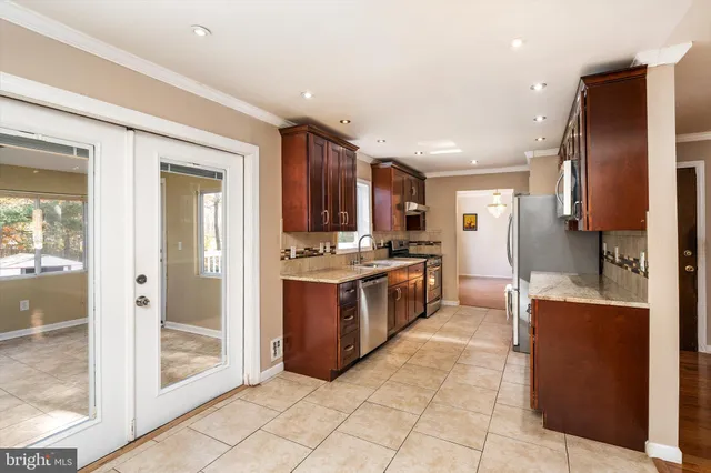 a large kitchen with stainless steel appliances kitchen island granite countertop a refrigerator and a sink
