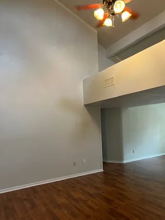 a view of an empty room with wooden floor and chandelier