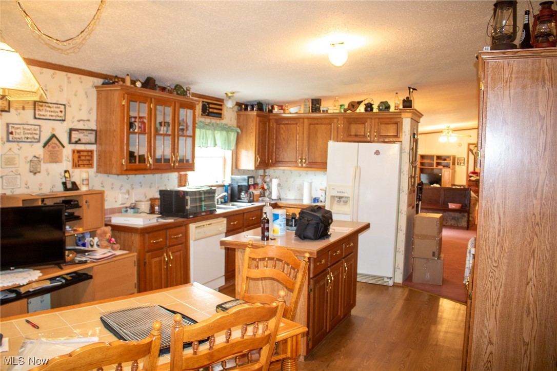 61691 Wintergreen Road Lore City, OH 43755 - Photo 26 of 50 Kitchen with white appliances, a textured ceiling, brown cabinets, a center island, and glass insert cabinets