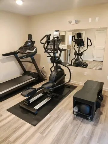 a room with gym equipment and wooden floor