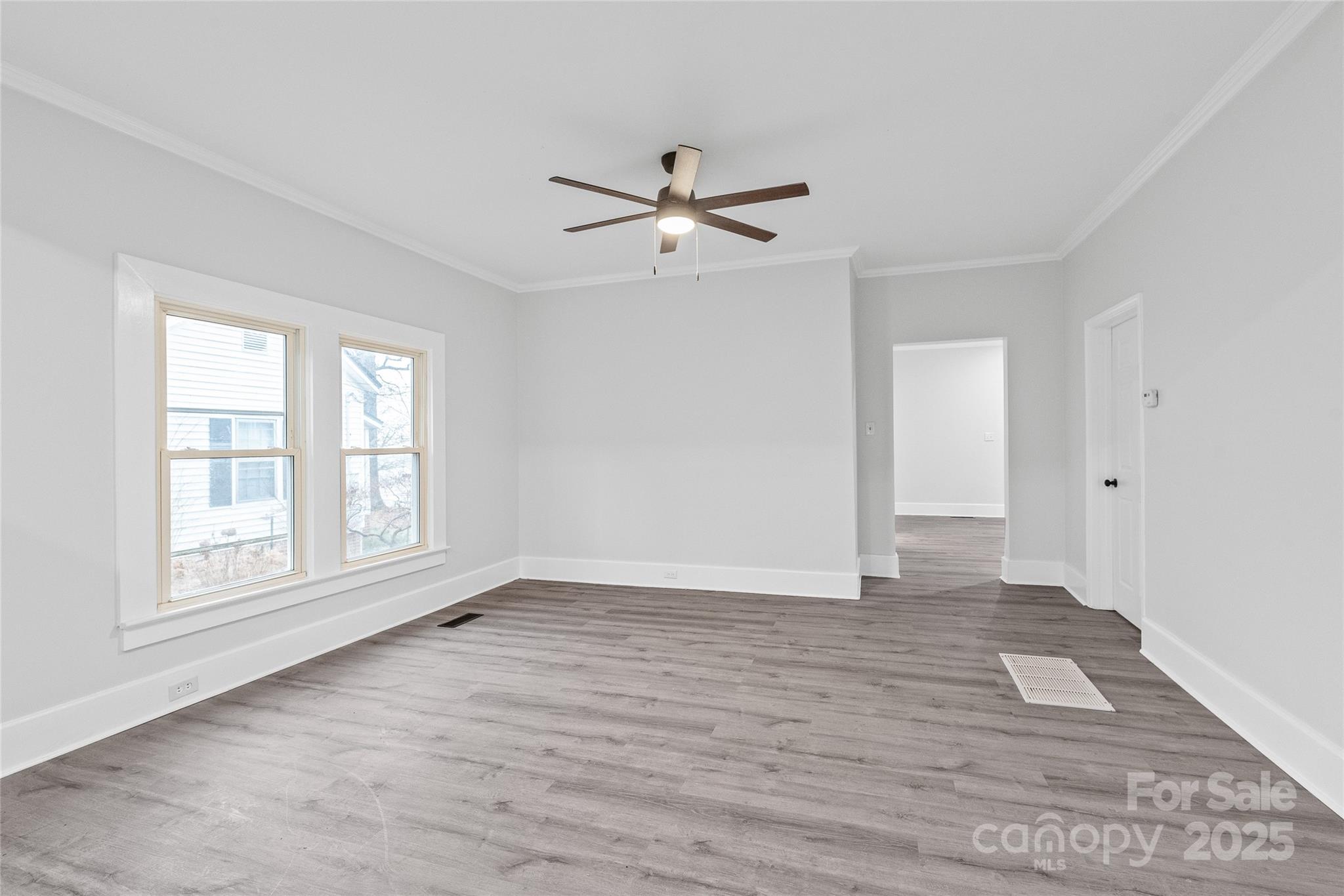 63 3rd Street Northwest Concord, NC 28027 - Photo 13 of 28 an empty room with wooden floor ceiling fan and windows