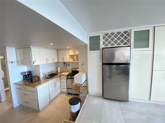 a kitchen with stainless steel appliances kitchen island granite countertop a refrigerator a stove a sink and a dining table