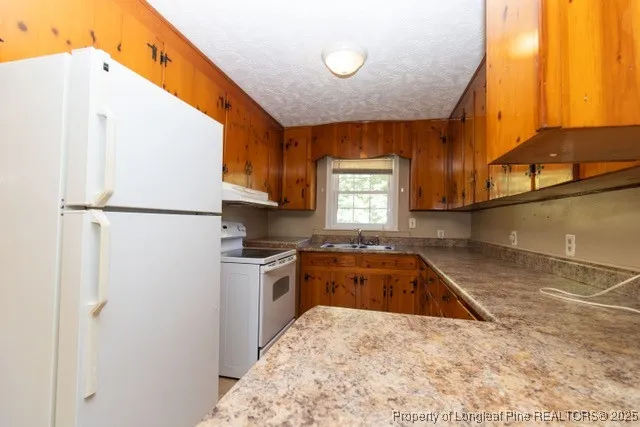 a kitchen with a refrigerator a stove top oven and a sink