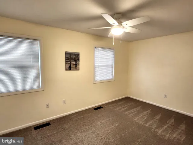 an empty room with a ceiling fan and window