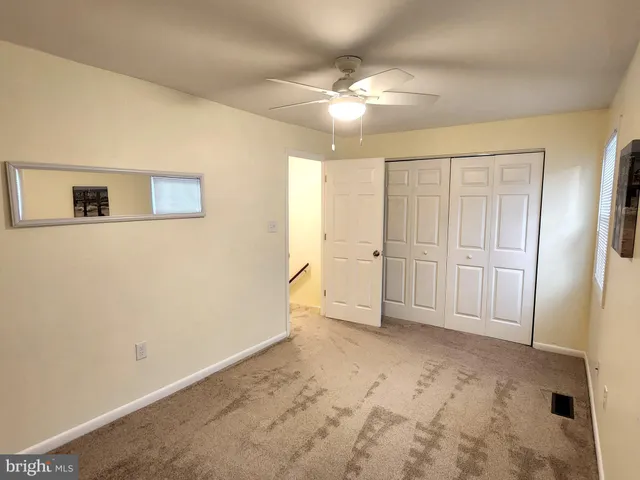 an empty room with a chandelier fan and windows