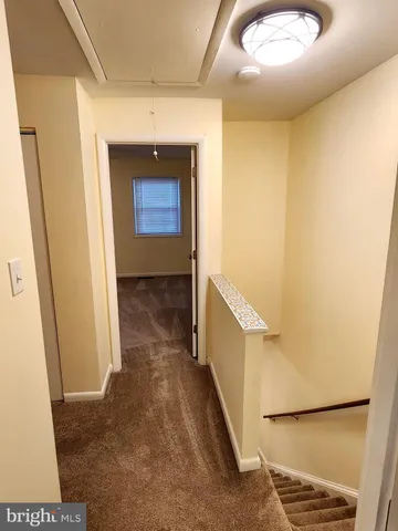 a view of a hallway with wooden floor and a bathroom