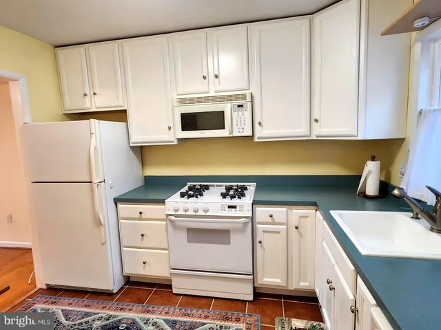 a kitchen with white cabinets and white appliances