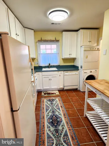 a kitchen with granite countertop a refrigerator a stove a sink and white cabinets