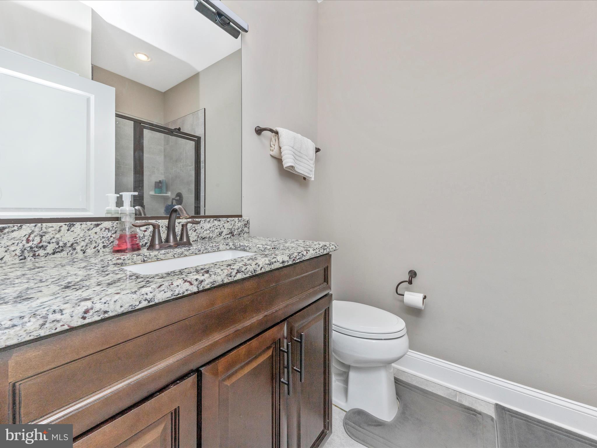 14671 Sugarland Road Poolesville, MD 20837 - Photo 33 of 62 a bathroom with a granite countertop sink a toilet and mirror