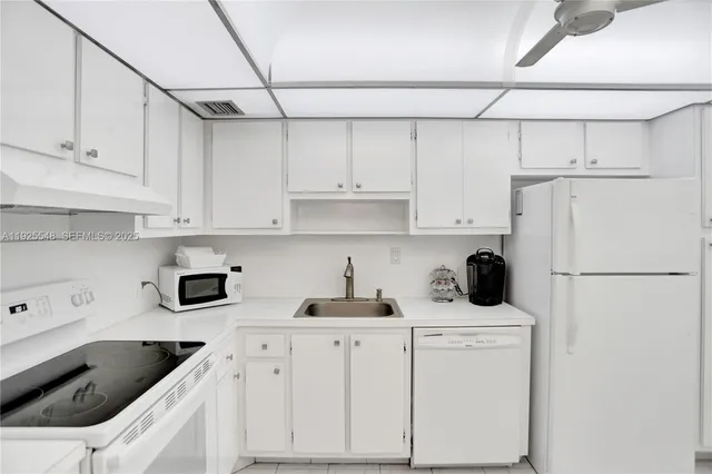 a kitchen with white cabinets and refrigerator