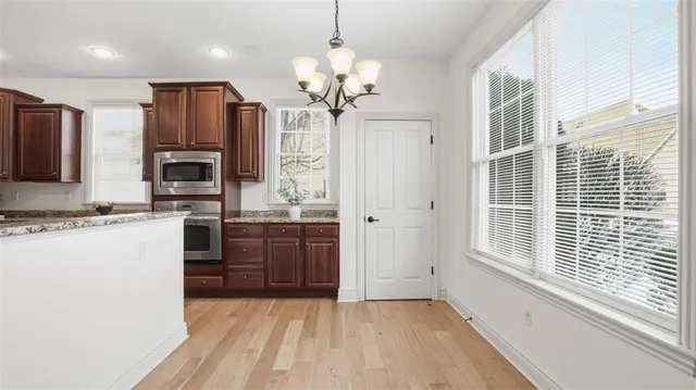 a kitchen with stainless steel appliances granite countertop a refrigerator a oven a sink with a dining table and chairs