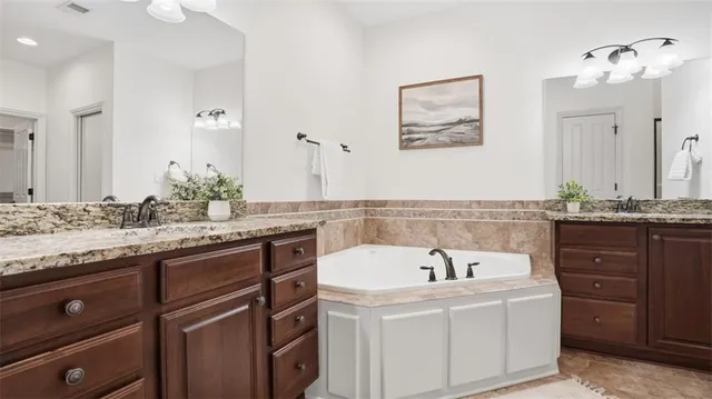 a bathroom with a granite countertop sink and a bathtub