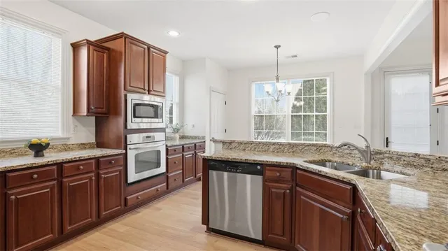 a kitchen with stainless steel appliances granite countertop a sink and wooden cabinets