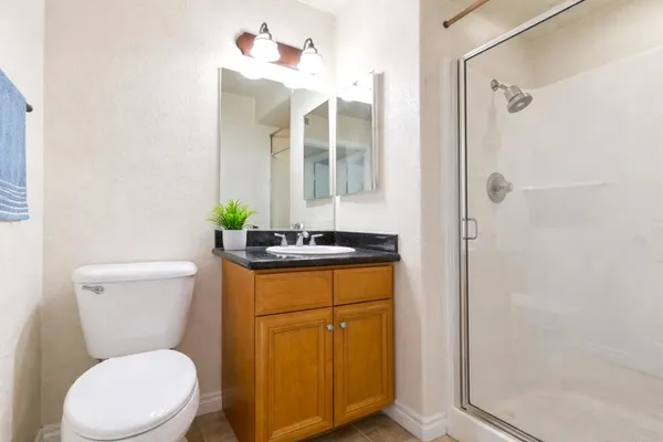 a bathroom with a granite countertop toilet sink and mirror