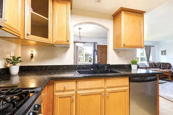 a kitchen with granite countertop a sink a stove and cabinets