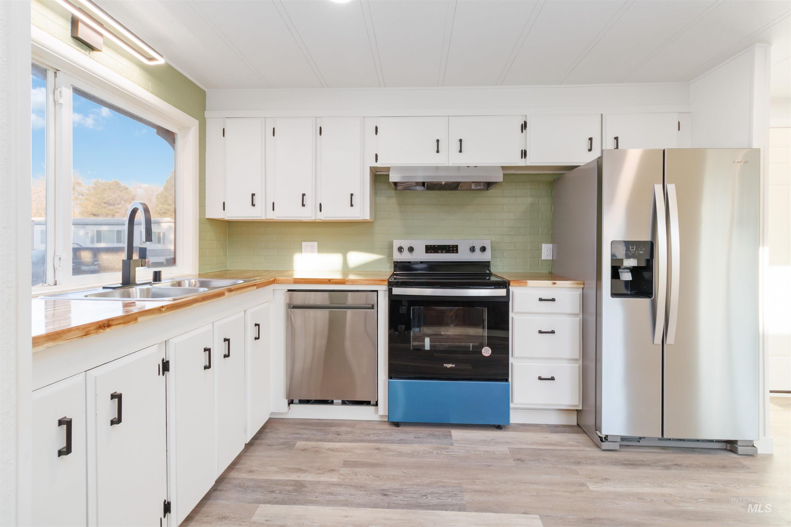 618 Empress Street Boise, ID 83713 - Photo 12 of 27 Kitchen featuring stainless steel appliances, backsplash, white cabinetry, light wood-type flooring, and under cabinet range hood