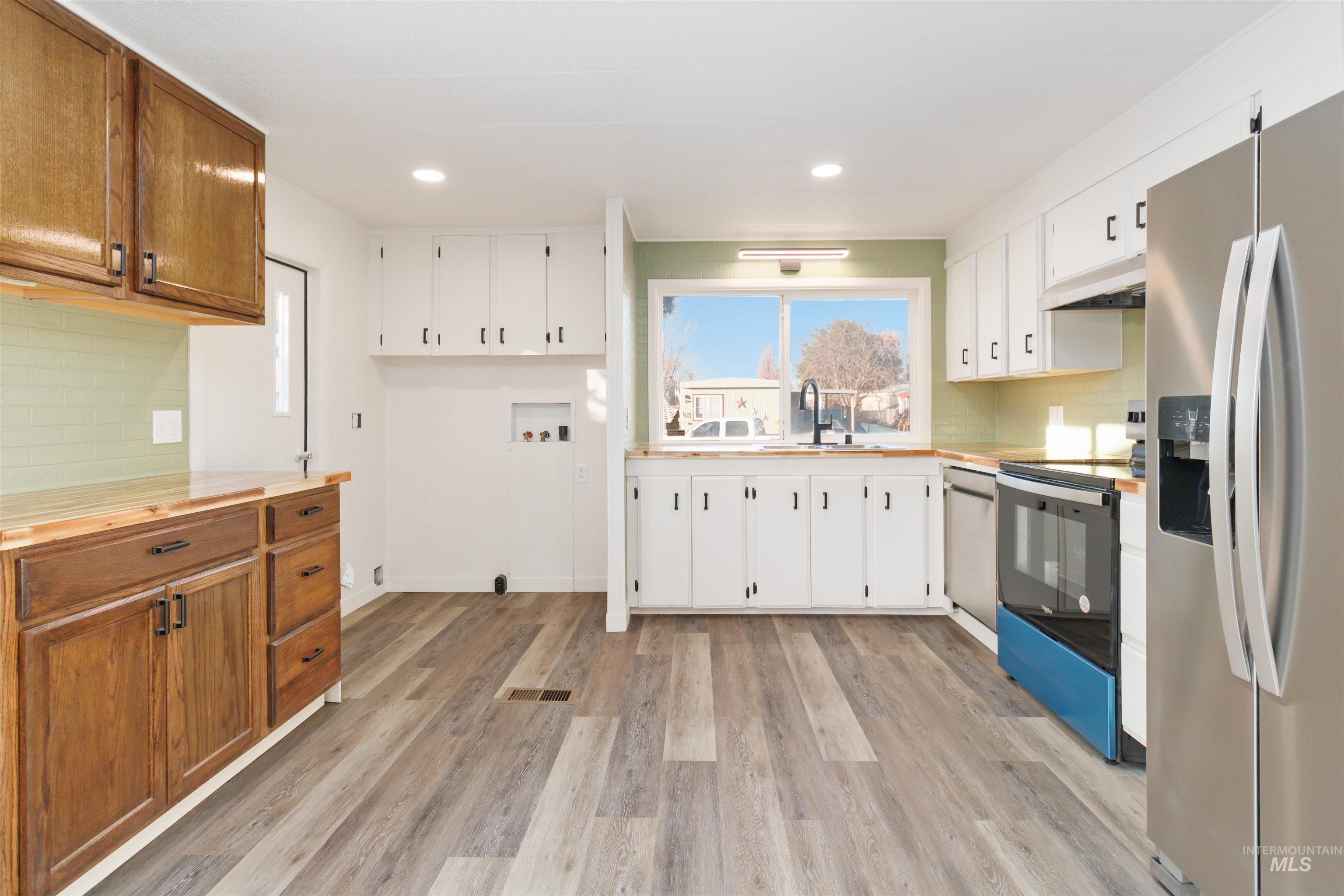 618 Empress Street Boise, ID 83713 - Photo 14 of 27 Kitchen with appliances with stainless steel finishes, decorative backsplash, white cabinetry, light wood-style floors, and recessed lighting
