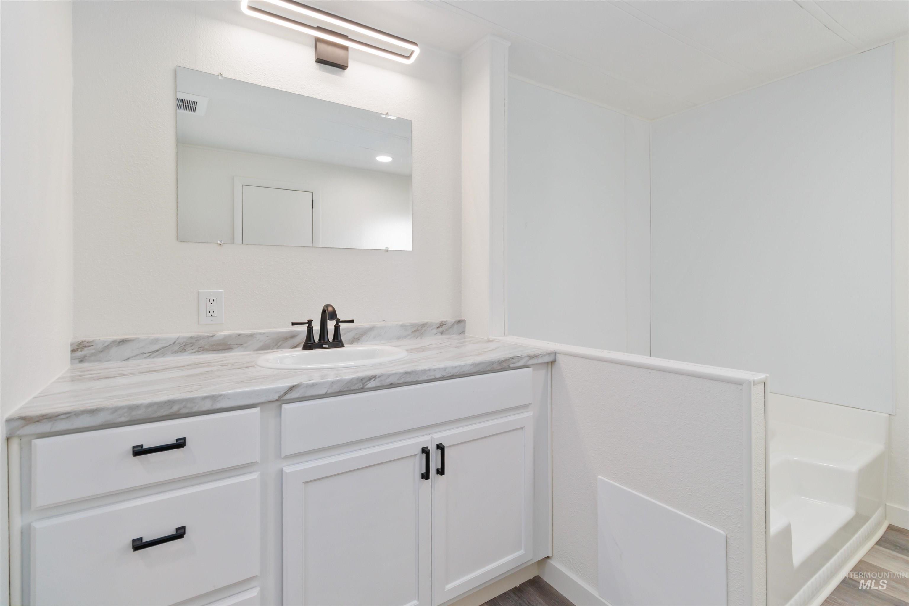 618 Empress Street Boise, ID 83713 - Photo 22 of 27 Bathroom featuring vanity, a garden tub, and wood finished floors