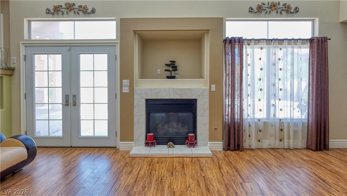 3704 North Campbell Road Las Vegas, NV 89129 - Photo 19 of 38 Hardwood floors complement a cozy fireplace, framed by glass-paned French doors and a bright window.