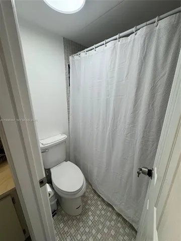 a white toilet sitting next to a shower curtain