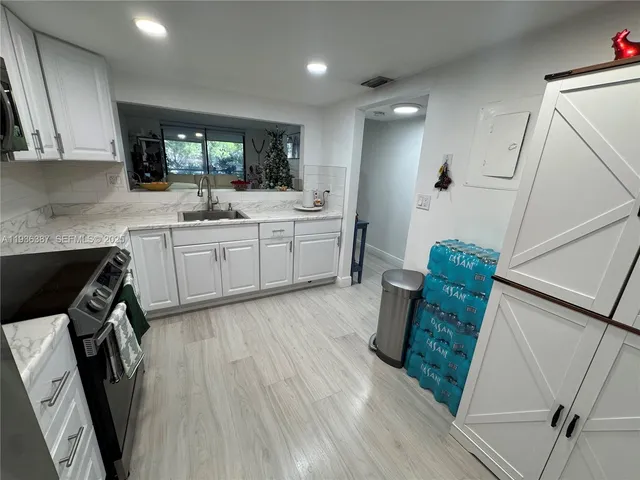 a large kitchen with a sink a microwave a stove and white cabinets