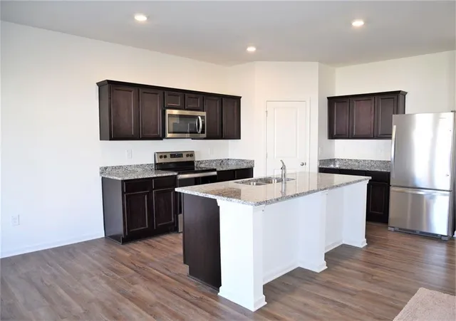 a kitchen with stainless steel appliances a stove a sink a microwave a refrigerator and cabinets