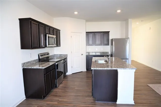 a kitchen with stainless steel appliances granite countertop a stove top oven a sink dishwasher and wooden cabinets